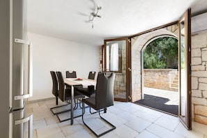 A dining area with a table and chairs, an open archway leading outside, and a ceiling fan. - 1963 Villa Ajeni by Perle di Puglia (San Michele Salentino)