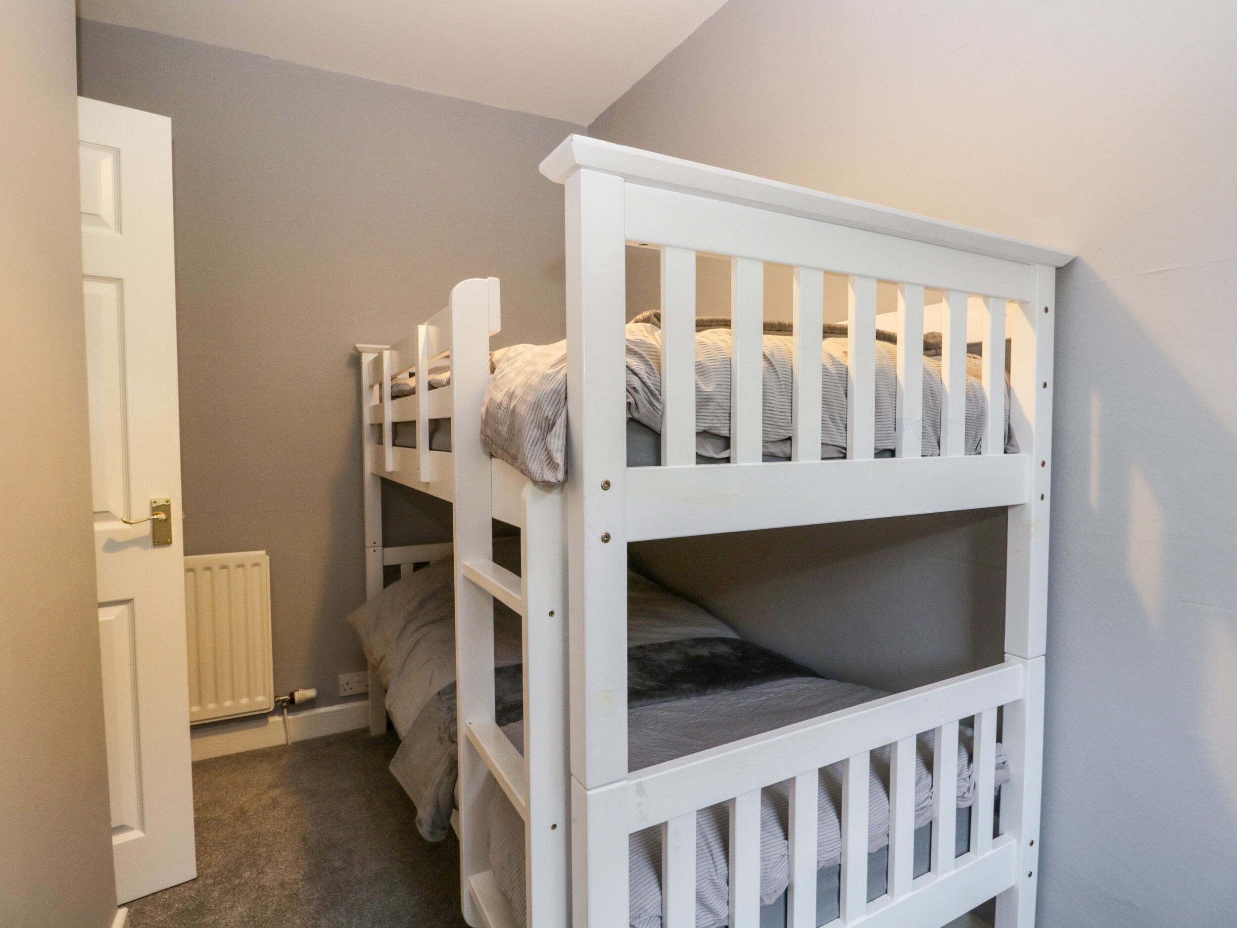 A bedroom with bunk beds, a radiator, and a door.