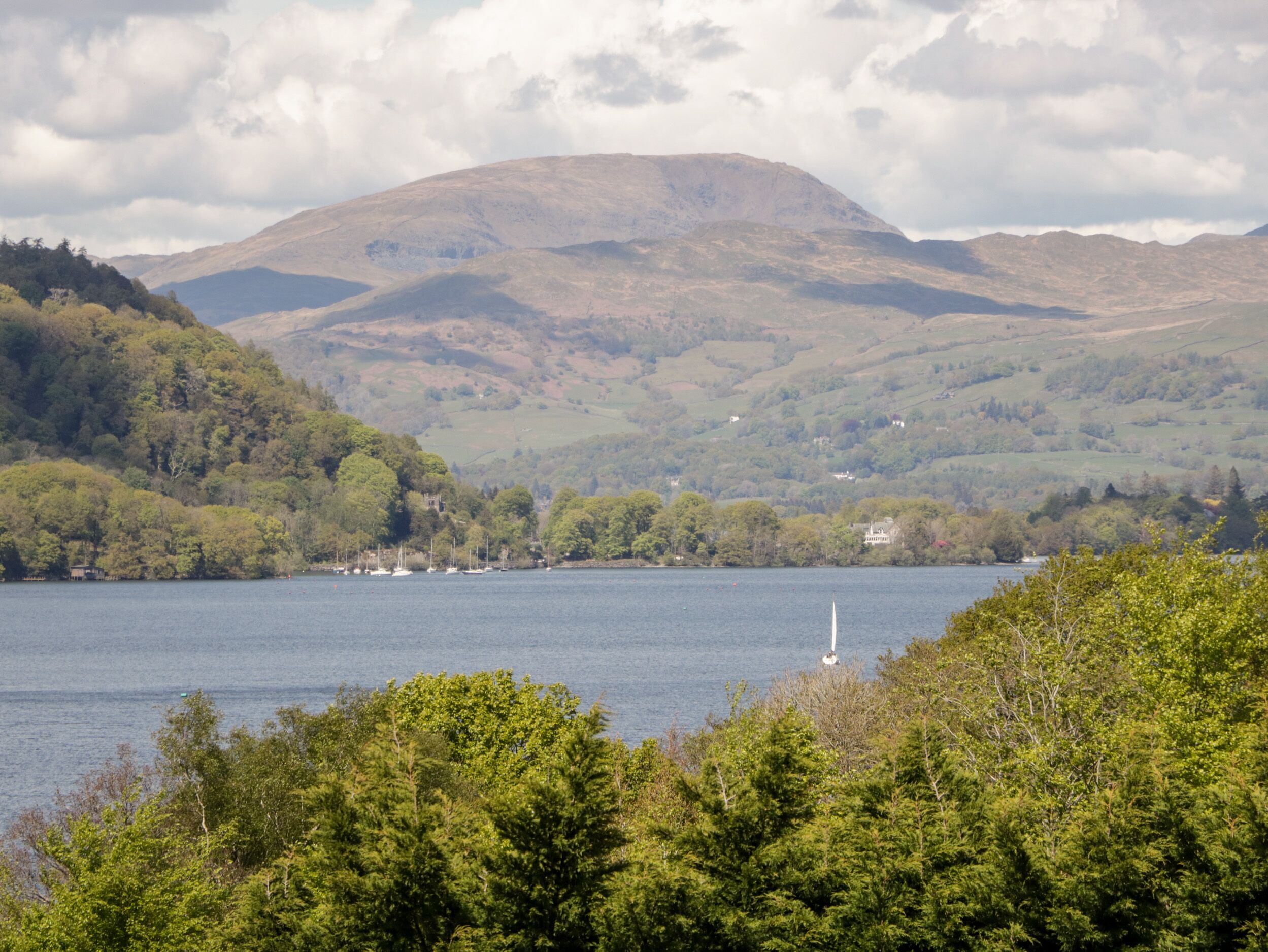 A lake surrounded by hills with a sailboat in the water.