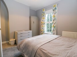 A bedroom with a bed, a wardrobe, a radiator, and a window with curtains.