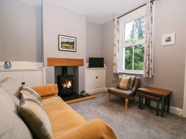 A cozy living room with a fireplace, a sofa, a chair, and a television.