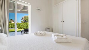 A hotel room with a large bed, a balcony with a piano, and a view of greenery.