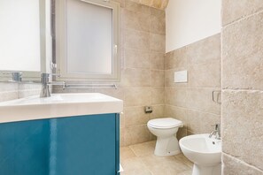 A bathroom with a blue cabinet, a white sink, a toilet, and a bidet. - 2769 Uliveto Valeria - Trullo Fico by Perle di Puglia (San Michele Salentino)