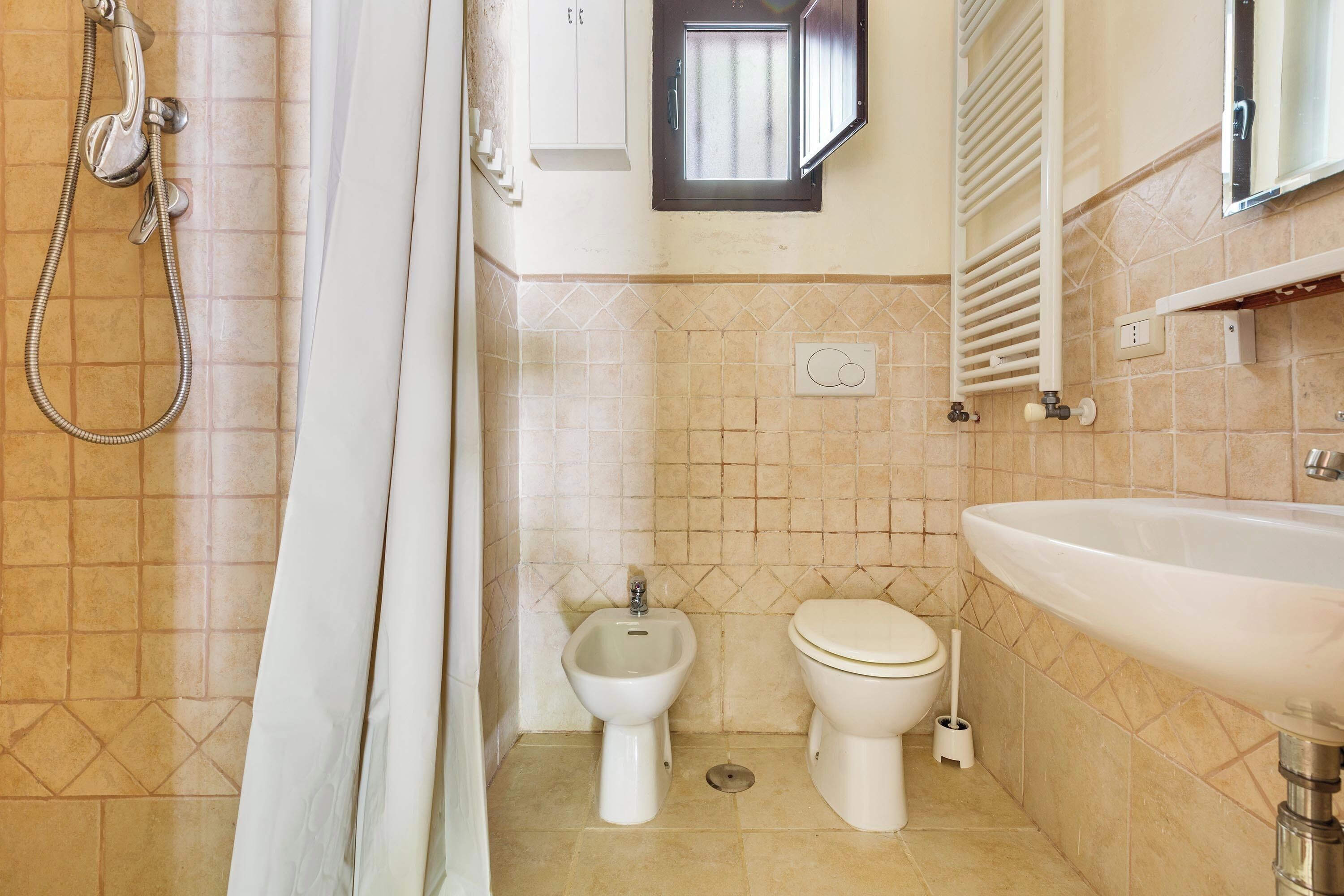 A bathroom with a shower, bidet, toilet, and sink.
