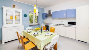 Une cuisine moderne avec des meubles blancs, une table à manger entourée de chaises jaunes et un luminaire suspendu jaune.