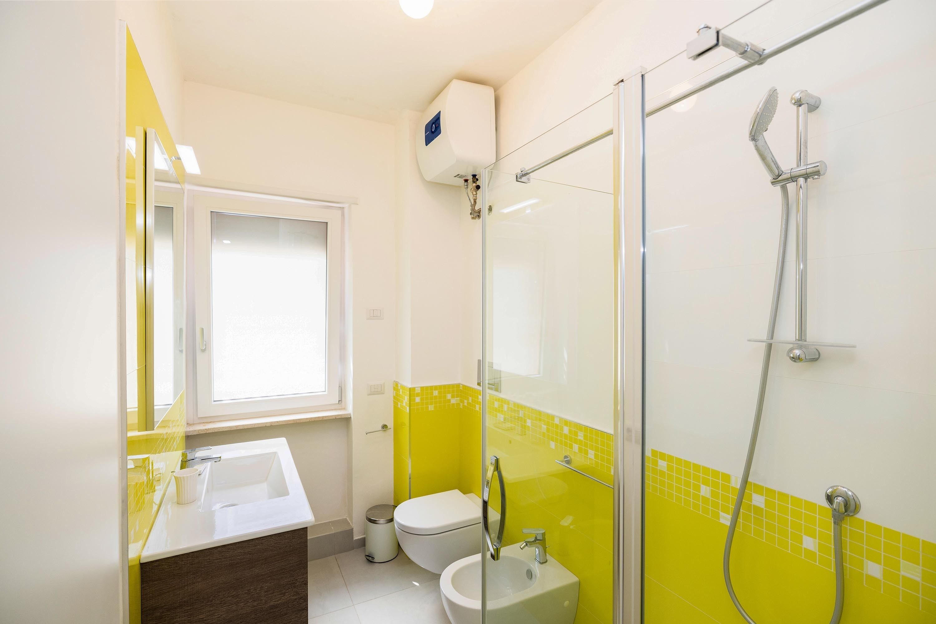 Une salle de bain avec une douche à parois de verre, un lavabo blanc et des toilettes.