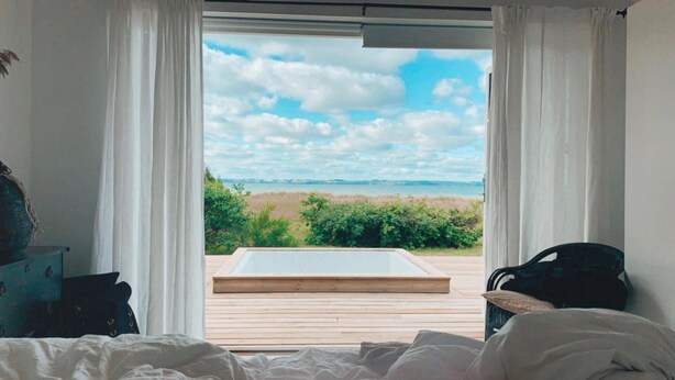 A bedroom with a large window overlooking a beach. - Stunning Ocean View and Private Beach (Nykobing Sjaelland)