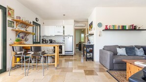 A modern kitchen with white cabinets, a wooden dining table, and a gray sofa in the living area. - 2968 Villa Freude by Perle di Puglia (Carovigno)
