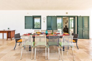 Guests can dine in style with a long table set for six, surrounded by comfortable chairs and a variety of tableware.