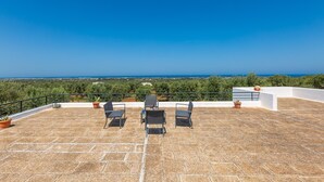 A rooftop terrace with three chairs and potted plants, overlooking a coastal landscape. - 2968 Villa Freude by Perle di Puglia (Carovigno)
