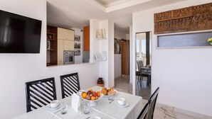 Un comedor con una mesa dispuesta para el desayuno, una cocina al fondo y un panel de madera decorativo sobre la mesa.