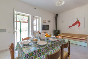 A dining area with a table set for four, a sofa, a TV, and a window with a view.