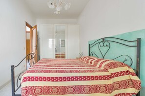 A bedroom with a bed, a wardrobe, and a mirror.