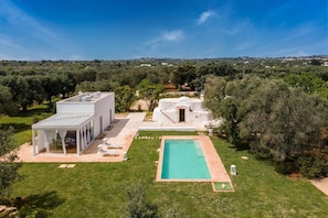 A modern villa with a swimming pool, outdoor seating, and a covered patio.