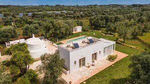 A modern house with a swimming pool, solar panels, and a lush garden. - 2329 Villa Kairos by Perle di Puglia (Ostuni)