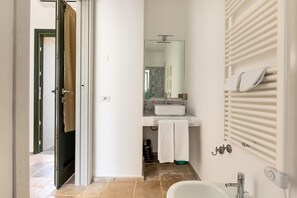 A bathroom with a white sink, a mirror, and a towel rack.