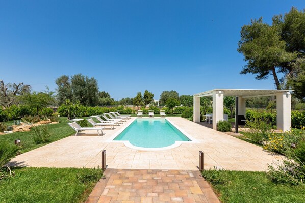 A rectangular swimming pool with a tiled deck, surrounded by lounge chairs and a pergola structure. - 2921 Villa La Seta by Perle di Puglia (San Vito dei Normanni)