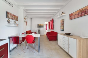 A modern kitchen with white cabinetry, red chairs, and a dining table. - 2535 Appartamento Red - Villa Sogno Blu by Barbarhouse (San Vito dei Normanni)
