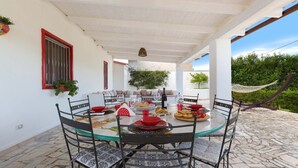 A covered outdoor dining area with a round table, chairs, and a variety of food and drink items. - 2535 Appartamento Red - Villa Sogno Blu by Barbarhouse (San Vito dei Normanni)