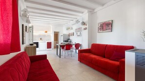 A modern living room with red sofas, a dining area, and a kitchen in the background. - 2535 Appartamento Red - Villa Sogno Blu by Barbarhouse (San Vito dei Normanni)