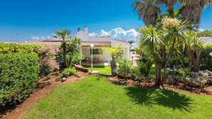 Una casa con jardín, patio y cielo azul despejado.