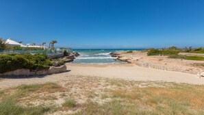 A beach with clear skies, rocky shoreline, and sparse vegetation. - 2374 Villa Costa Merlata by Perle di Puglia (Ostuni)