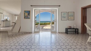 A spacious room with a view of the beach, a staircase, and a small table with a lamp. - 2374 Villa Costa Merlata by Perle di Puglia (Ostuni)