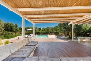 A covered outdoor area with a pool, wooden deck, and seating. - 2971 Villa Piti by Perle di Puglia (Carovigno)