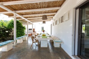 A covered outdoor dining area with a long table, benches, and a pergola overhead. - 2971 Villa Piti by Perle di Puglia (Carovigno)