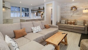 Ein modernes Wohnzimmer mit einer Eckcouch, einem Holztisch und einem gemütlichen Kamin.