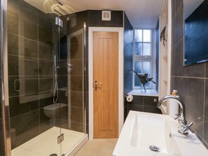 Une salle de bain moderne avec une douche à parois de verre, une porte en bois, un lavabo avec un miroir et une fenêtre donnant sur un beau paysage.