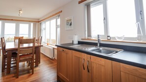 A modern kitchen with wooden cabinets, a black countertop, and a large window. - Learig (Buckie)