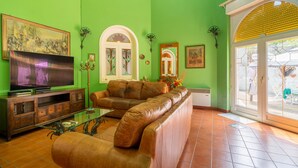 A living room with a large flat-screen TV, leather sofa, and a glass coffee table.