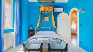A bedroom with a four-poster bed, a white door, and a blue wall.