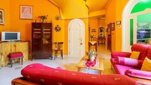 A room with a staircase, a television, a cabinet, a sofa, and a door.