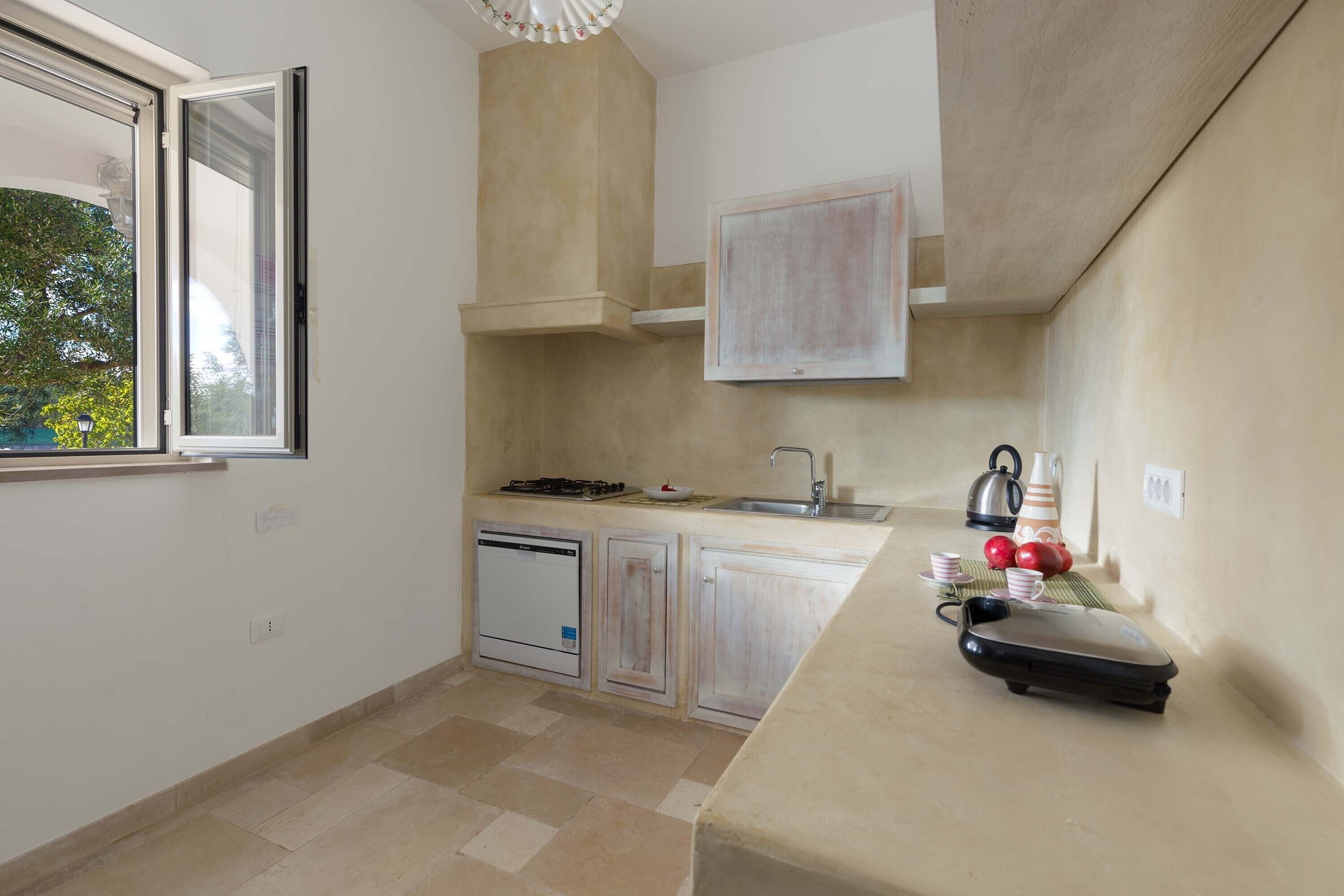 A small kitchen with a window, a sink, a stove, and a dishwasher.