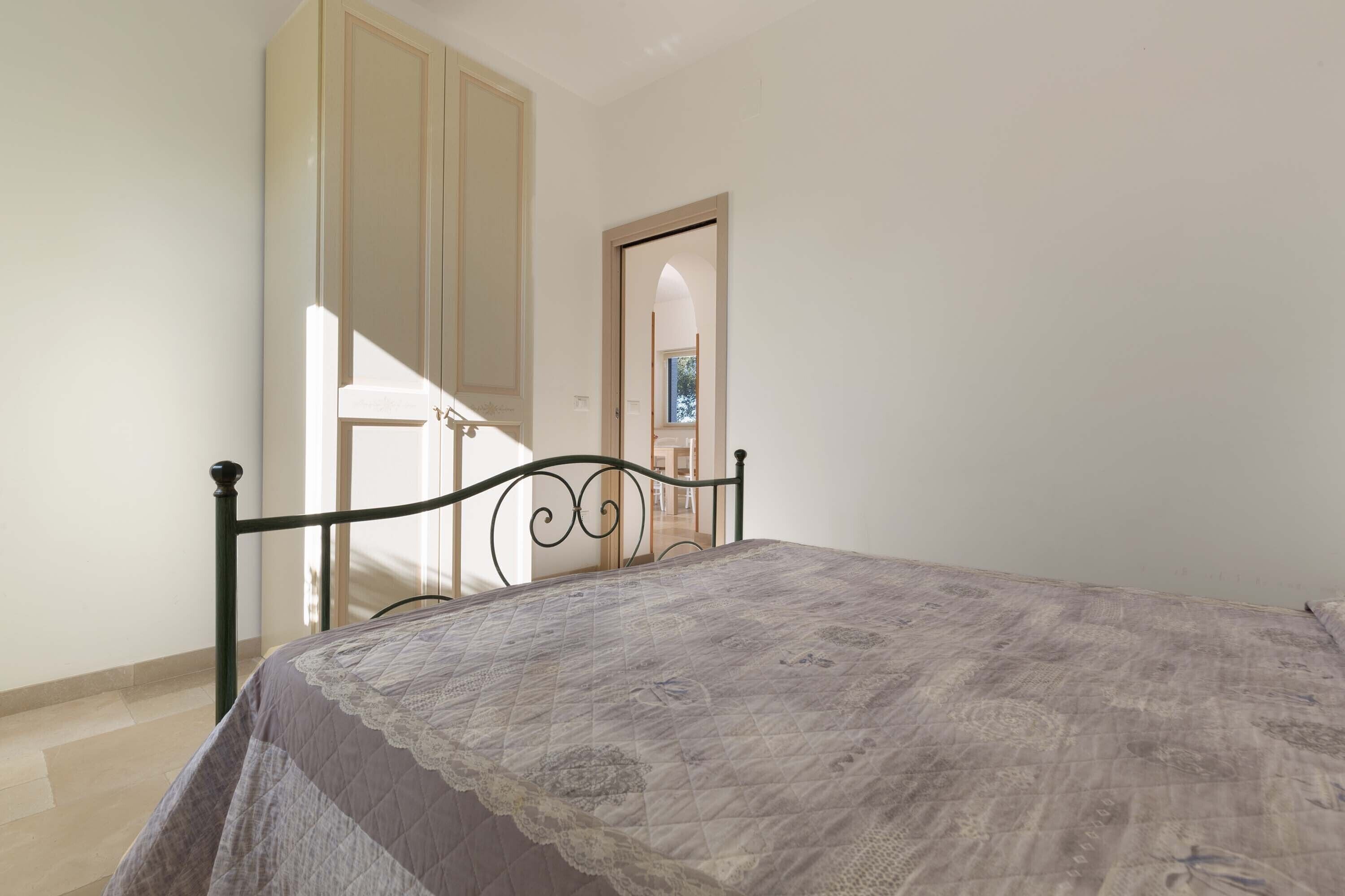 A bedroom with a bed, a wardrobe, and a door leading to another room.