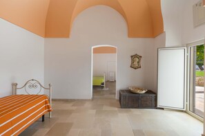 A bedroom with a bed, a small table, a decorative bowl, and a door leading to another room.