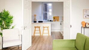 A modern kitchen with white cabinets, a window, and a small island with stools. - The Fulham Escape - Alluring 5BDR Flat (London)