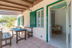 Une terrasse extérieure avec des meubles en bois et une table dressée pour le repas.