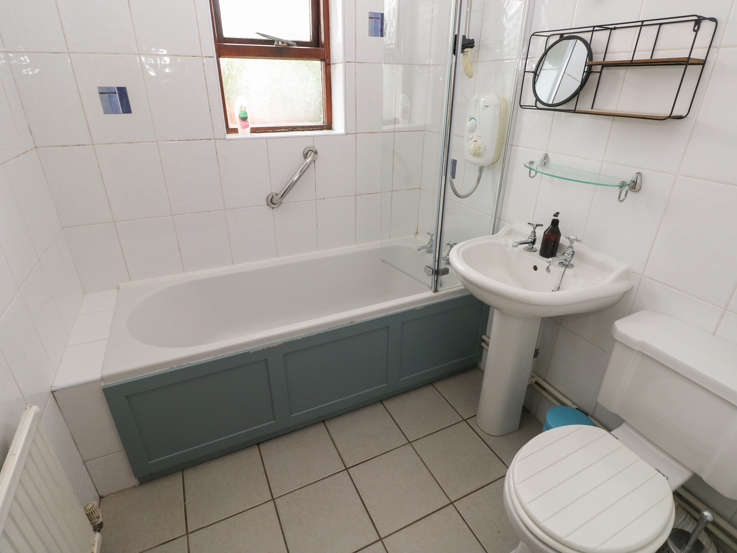 Et badeværelse med badekar, håndvask, toilet og et vindue.