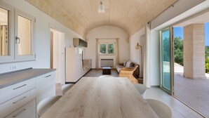 Een moderne keuken met een grote houten tafel, inbouwapparatuur en uitzicht op de omgeving door grote ramen.