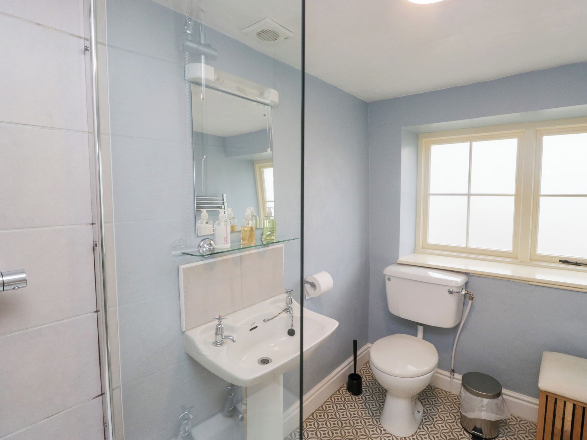 Une salle de bain avec une douche à parois de verre, un lavabo, des toilettes et une fenêtre.
