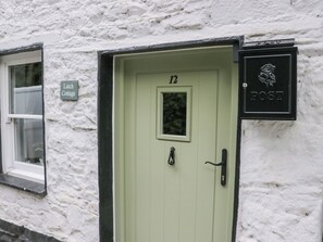 A light green door with the number 12, a small window to the left, and a 'POST' sign with a rose emblem to the right. - Latch Cottage (Keswick)