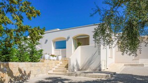 A modern building with a white facade, a set of stone steps leading to a door, and a clear blue sky.