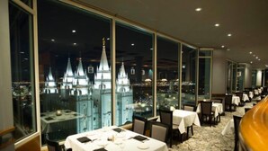 Ein Restaurant mit gedeckten Tischen, großen Fenstern mit Stadtblick und modernem Interieur.