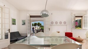 Ein modernes Wohnzimmer mit einem Glastisch, weißen Stühlen, einem roten Sofa und einem schwarzen Couchsofa.