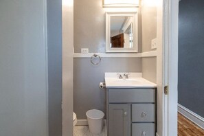 A small bathroom with a white sink, a mirror, and a toilet. - Cozy, Clean and Centrally Located (Grand Rapids)