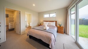 Un dormitorio con una cama grande, mesitas de noche, un armario y vistas al exterior.