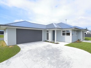 Una casa a un piano con un garage grigio, un portico coperto e un tetto in metallo inclinato.